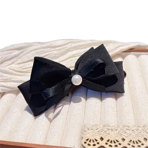 Elegant black satin bow hair clip with a central pearl embellishment for women