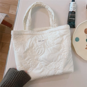 Close-up of white quilted tote bag with floral texture and simple wish logo label