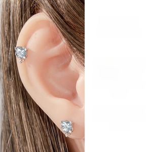 Detail of a light blue heart-shaped zircon earring on a silicone ear model