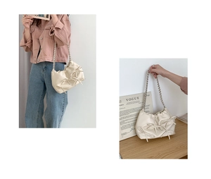 Detail of cream pleated PU leather shoulder bag featuring 3D bows and silver chain strap