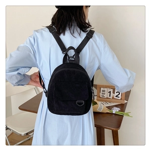Detail view of the black corduroy texture and adjustable straps of this mini backpack