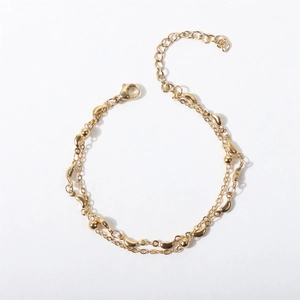 Detail of golden double-layer chain bracelet with metal beads and lobster clasp closure