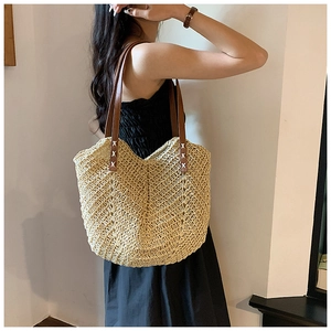 Détail du sac cabas en paille montrant le tissage en V et les coutures du cuir brun