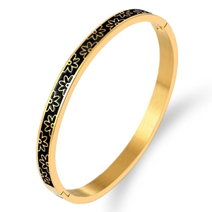 Gold stainless steel bangle with black enamel flower pattern shown at a 45-degree angle