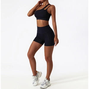 Detail of high-waist yoga shorts and one-shoulder sports bra set in black athletic fabric