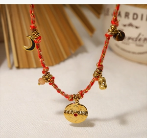Detail of red woven necklace with 18K gold pendants and black enamel moon charms