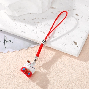 Japanese Maneki Neko lucky cat pendant with red cord on white textured stone surface