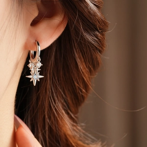 Close-up of star pendant earring with light blue gemstone worn on a model ear