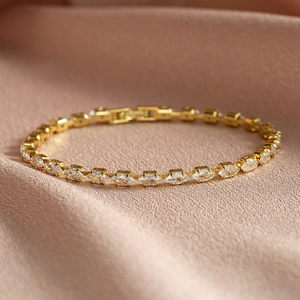 Elegantes vergoldetes Tennisarmband mit Zirkonia-Steinen auf weichem rosa Stoff