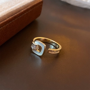 Detailed macro of gold plated square ring with white enamel and sparkling zircon accents