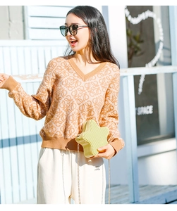 Detail of yellow star-shaped jelly bag with chain strap worn with a patterned sweater