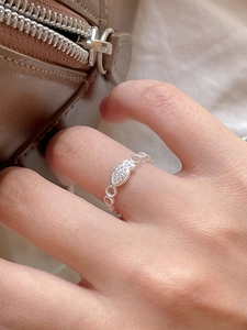 Detail of silver fish-shaped ring with zircon inlay worn on a finger in high quality