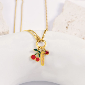 Golden cherry necklace with AMOUR charm and red zircon on a minimalist display