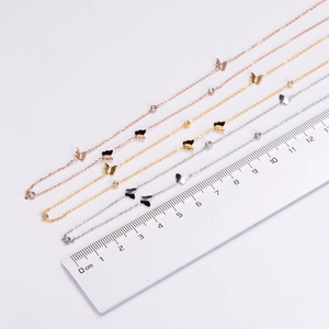 Gros plan de colliers pendentifs papillon avec règle montrant la taille et les détails