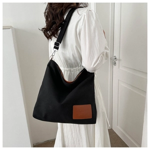 Detail of black canvas tote with brown leather tag and sturdy silver hardware hooks