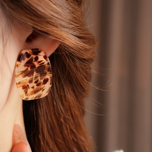 Detail of square leopard print acrylic earring worn by a model for a vintage look