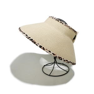 Close-up of foldable straw sun hat with leopard print trim on a black metal display stand