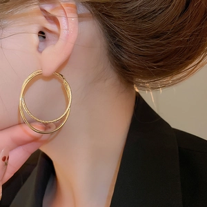 Macro detail of 18k gold plated double layered cross hoop earrings on model ear