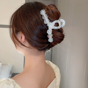 Pince à cheveux blanche irisée sur chignon avec texture nacrée style coquillage élégant