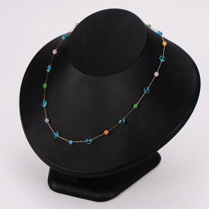 Gold chain necklace with blue floral beads and multicolored stones on a black bust