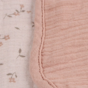 Detail of soft muslin cotton baby blanket featuring floral print and pink trim