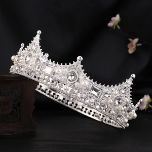 Detail of silver Baroque crown with pearls and crystals on a vintage wooden stand