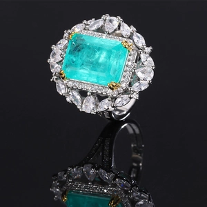 Macro shot of an emerald-cut green gemstone ring with marquise side stones and gold claws
