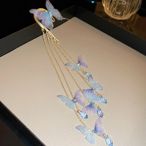 Détail du contour d'oreille papillon en tissu avec longues franges dorées et cristaux