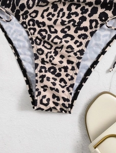 Detail view of leopard print bikini bottom with side ties on a white stone background