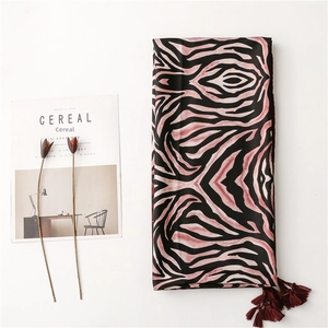 Close-up of zebra pattern scarf with deep red tassel balls and bohemian aesthetic detail