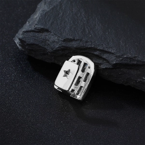Macro view of silver star cutout hip hop grillz tooth cap on a black rock base