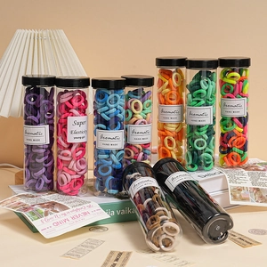 Detail of colorful elastic hair bands in a transparent cylinder with a minimal label