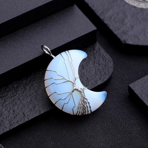 Macro shot of silver wire wrapped tree of life on opal moon pendant over black texture