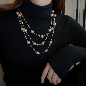 Close-up of champagne pearl multi-layer necklace on a black turtleneck sweater