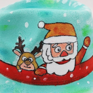 Gros plan d'un chapeau en feutre turquoise avec motifs de Père Noël et renne peints