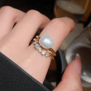Macro shot of irregular baroque pearl and glittering zircons on a gold-plated ring band
