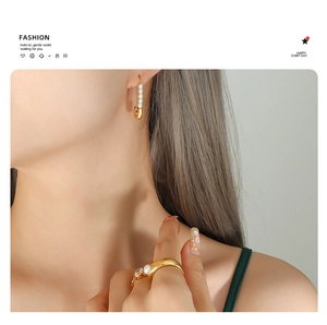 Detail of 18K gold paperclip earring with pearls and matching zircon ring on model
