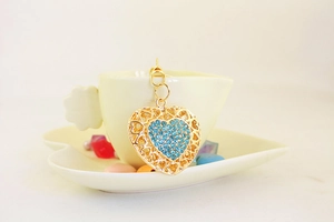 Detailed view of a gold heart pendant with blue rhinestones in a decorative cup