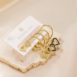 Golden stainless steel heart earring set featuring hoops and studs on stone pedestal