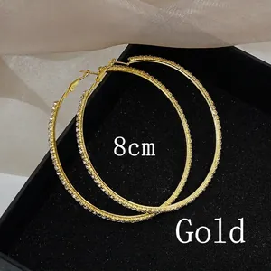Close-up of 8cm oversized golden hoop earrings with sparkling white rhinestones