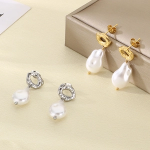 Macro detail of Baroque irregular pearls and lava-textured gold earrings on a jewelry stand