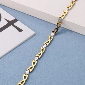 Detailed shot of two-tone gold and silver X-link metal chain bracelet on blue texture