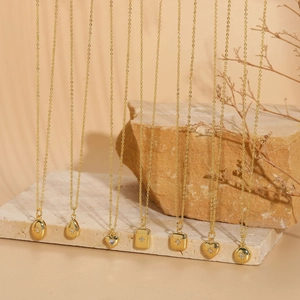 Detail of seven gold geometric necklaces with starburst-set zircons on stone background