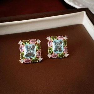 Macro detail of gold flower stud earring with blue, pink, and green zircon stones