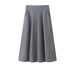 Gros plan sur la texture du tissu et les plis d'une jupe grise en tweed taille haute