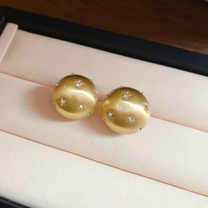 Macro detail of golden matte ball earrings featuring sparkling star-set crystals