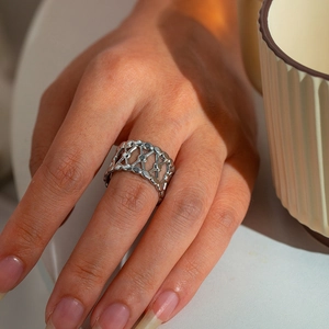 Close-up of a silver wide hollow mesh stainless steel ring worn on a finger