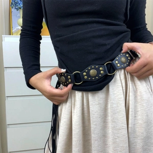 Detail of Y2K vintage black leather belt with gold rivets and floral buckles on a model