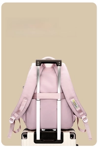 Pink travel backpack with a luggage strap secured to a suitcase handle for easy travel