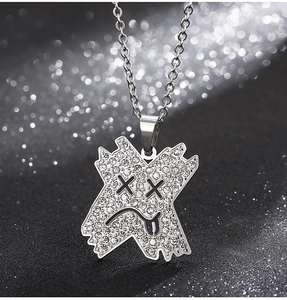 Gros plan d'un pendentif en croix argentée avec strass et détails de visage de dessin animé